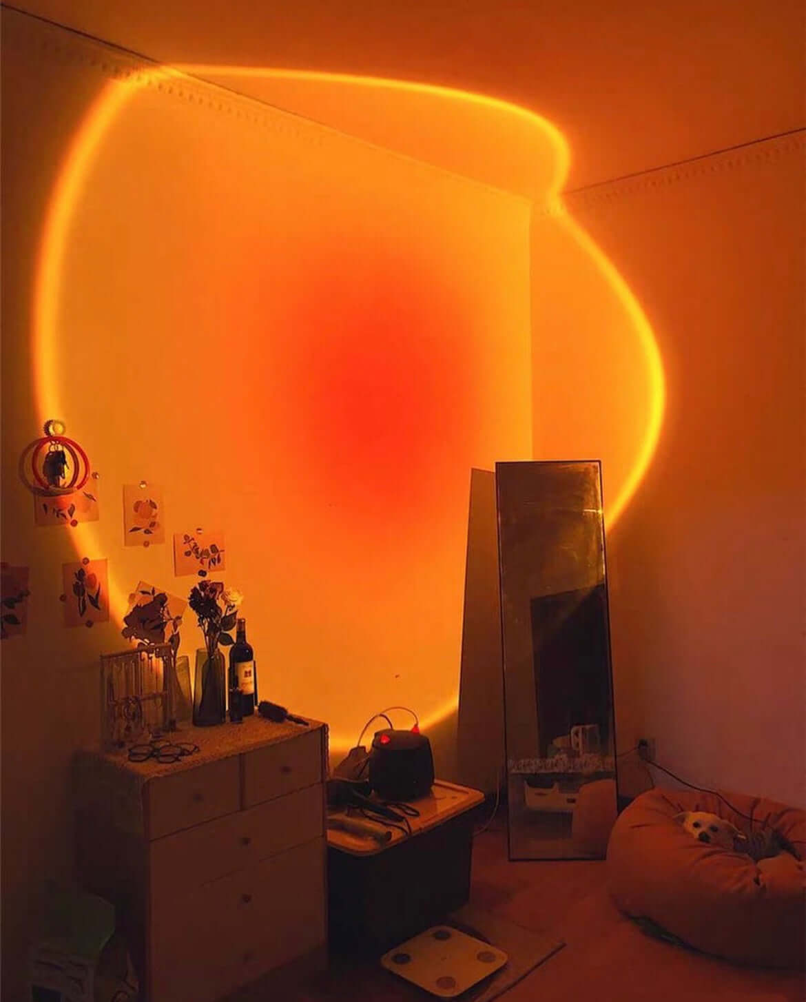 Sunset lamp projecting a warm orange and red glow on the wall, creating a relaxing vibe in a cozy room with soft lighting and boho decor.