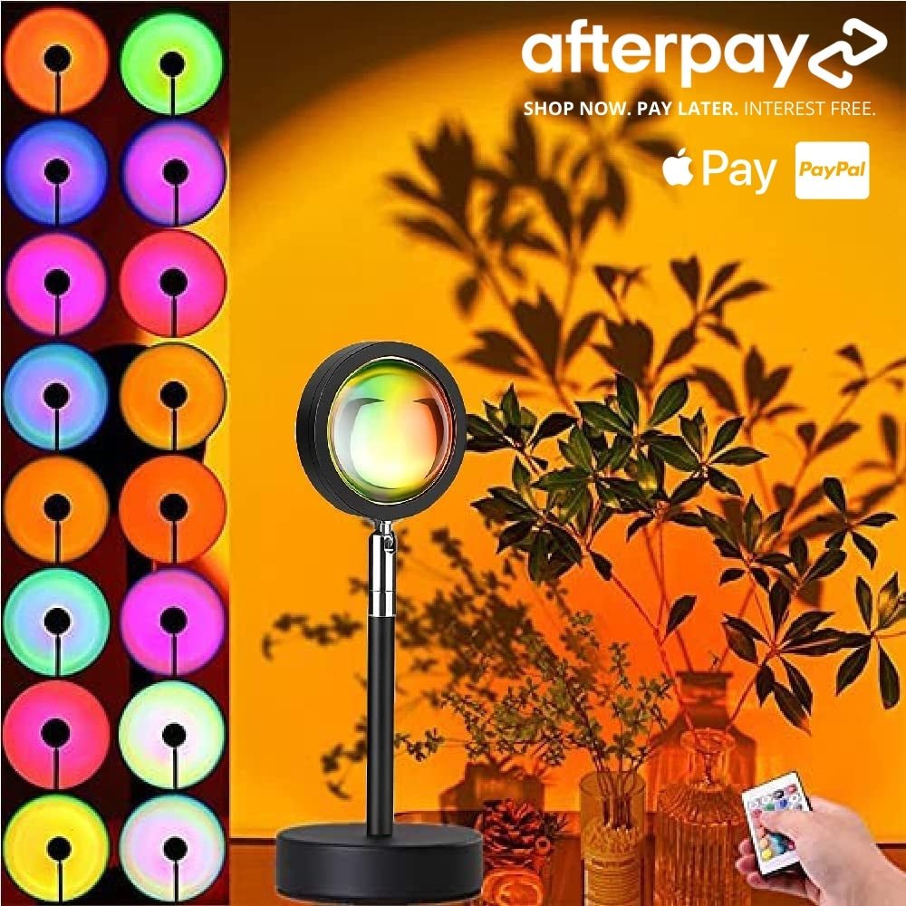 Multicolor sunset lamp with 16 adjustable color modes, remote control, and floral decor, casting a warm glow on an orange-toned wall.